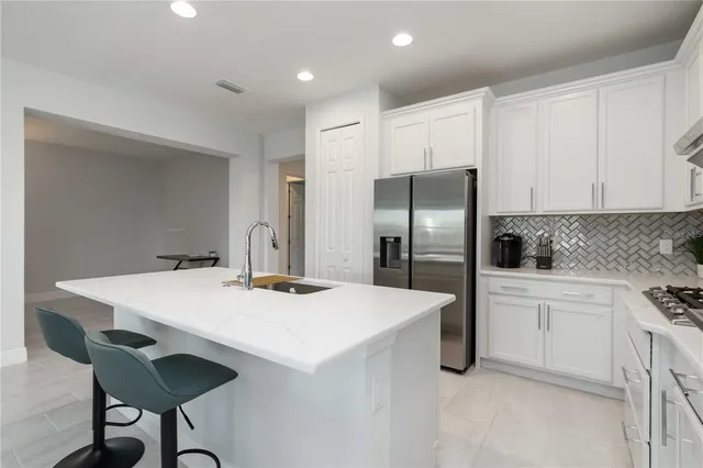 a kitchen with stainless steel appliances a refrigerator and white cabinets