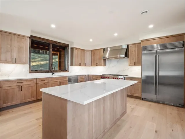 a large kitchen with a large counter top a sink stainless steel appliances and cabinets