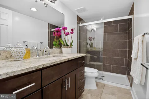 a bathroom with a granite countertop sink a toilet and shower