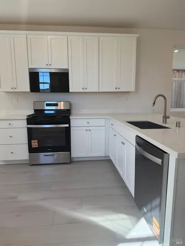a kitchen with granite countertop white cabinets and stainless steel appliances
