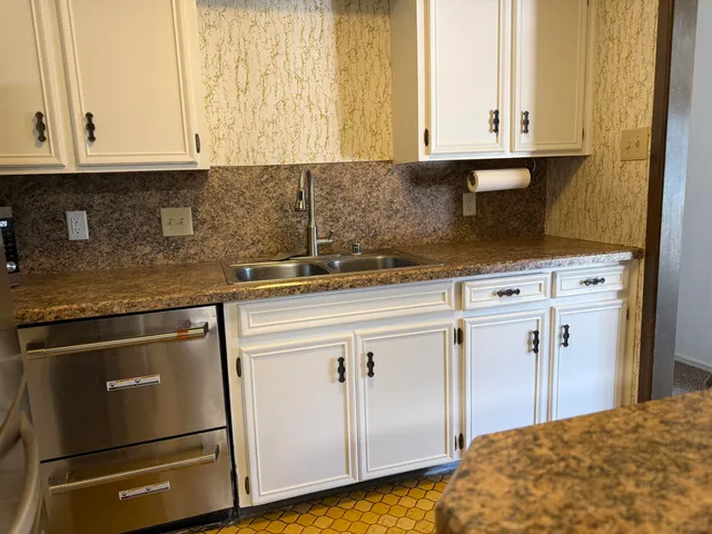 a kitchen with granite countertop white cabinets and sink