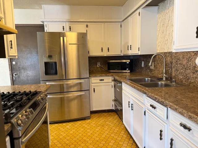 a kitchen with granite countertop a refrigerator stove and sink