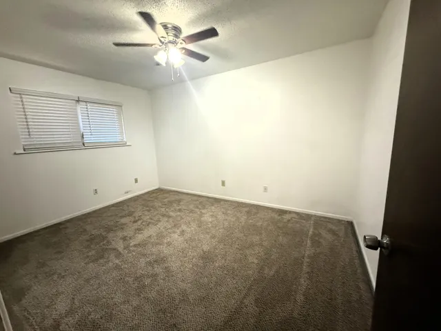 an empty room with a chandelier fan and a window