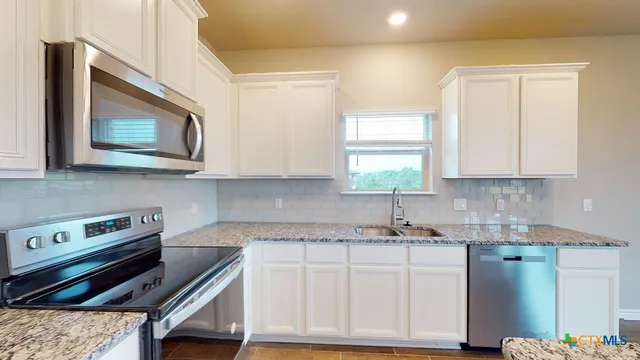 a kitchen with cabinets appliances a sink and a window