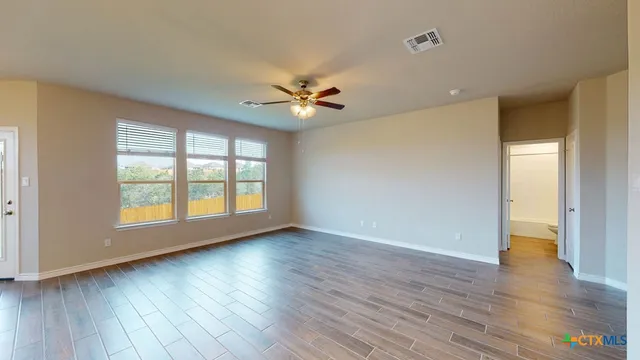 an empty room with wooden floor and windows