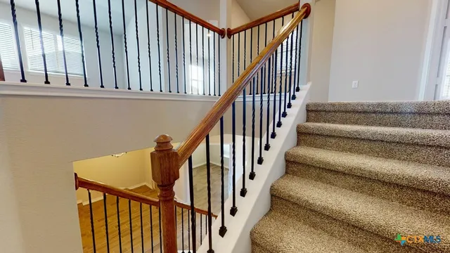 a view of staircase with railing and white walls
