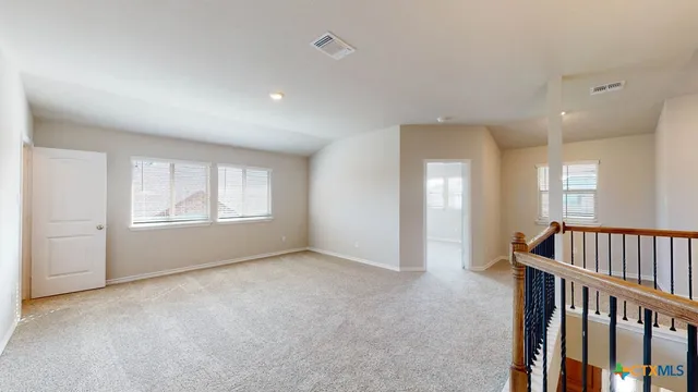 a view of an empty room with windows & cabinet