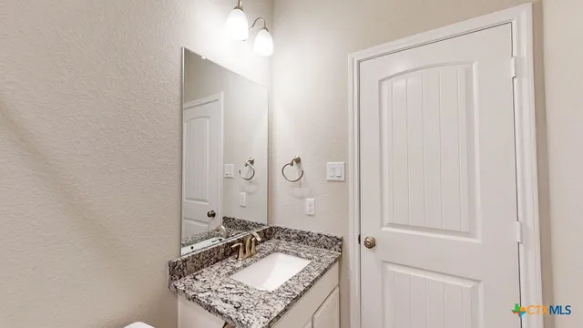 a bathroom with a granite countertop sink and a mirror