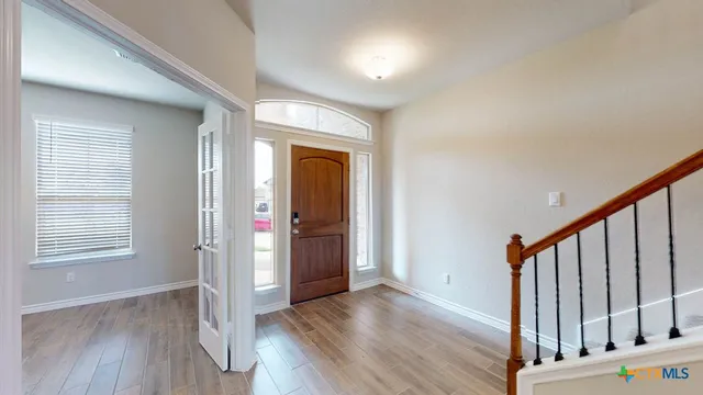 a view of an empty room with wooden floor and stairs