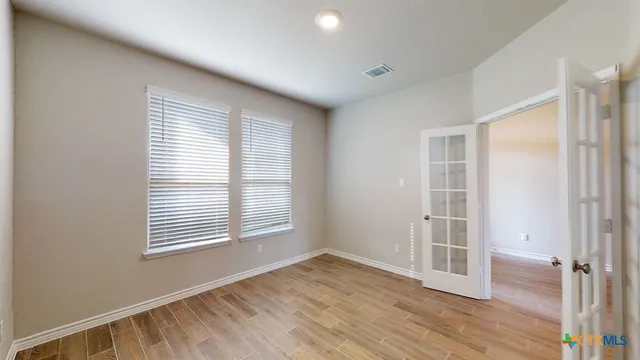 an empty room with wooden floor and windows