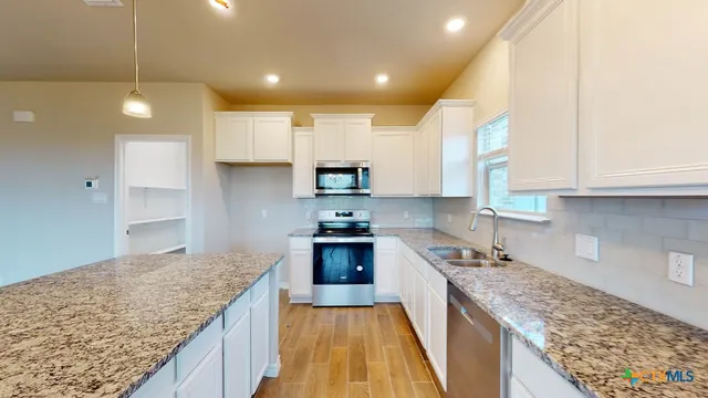 a kitchen with kitchen island granite countertop a stove and a sink