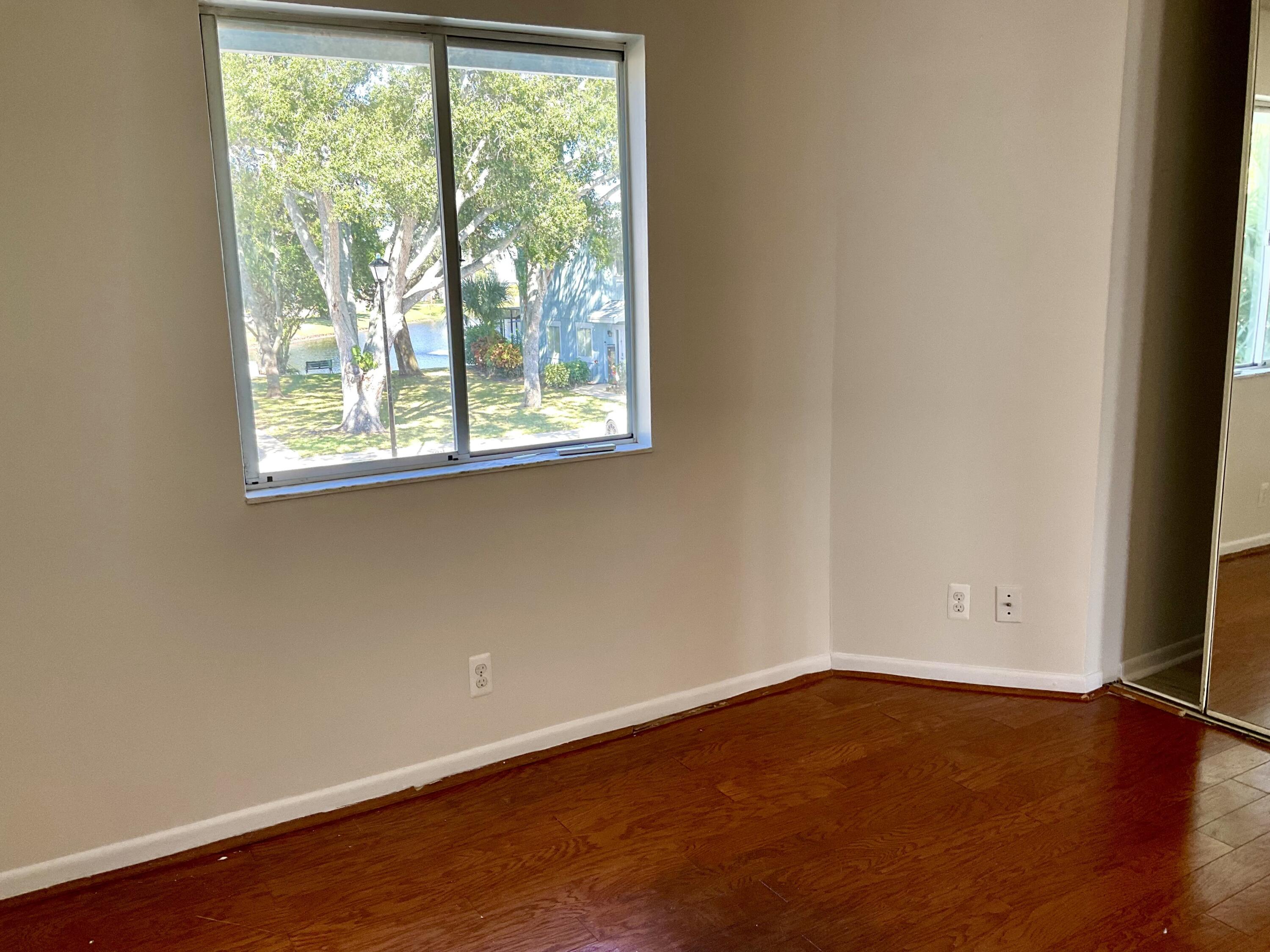 6262 Riverwalk Lane, Unit 3 Jupiter, FL 33458 - Photo 7 of 28 an empty room with wooden floor and windows