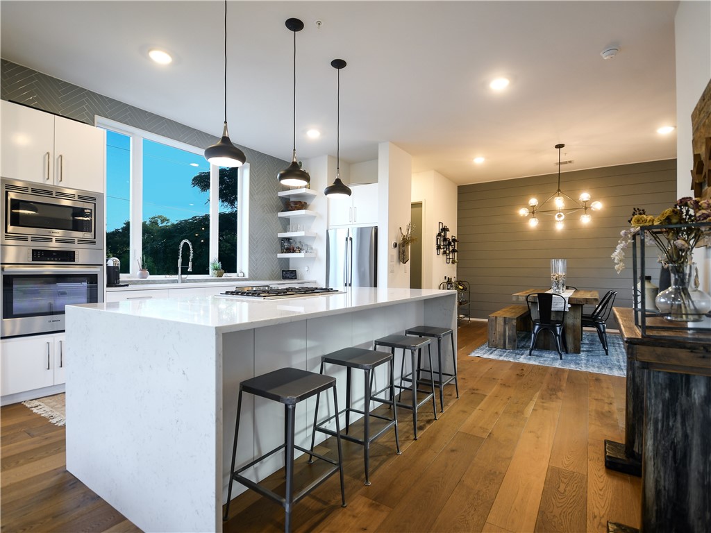 a large kitchen with a large counter top space a sink appliances and a living room