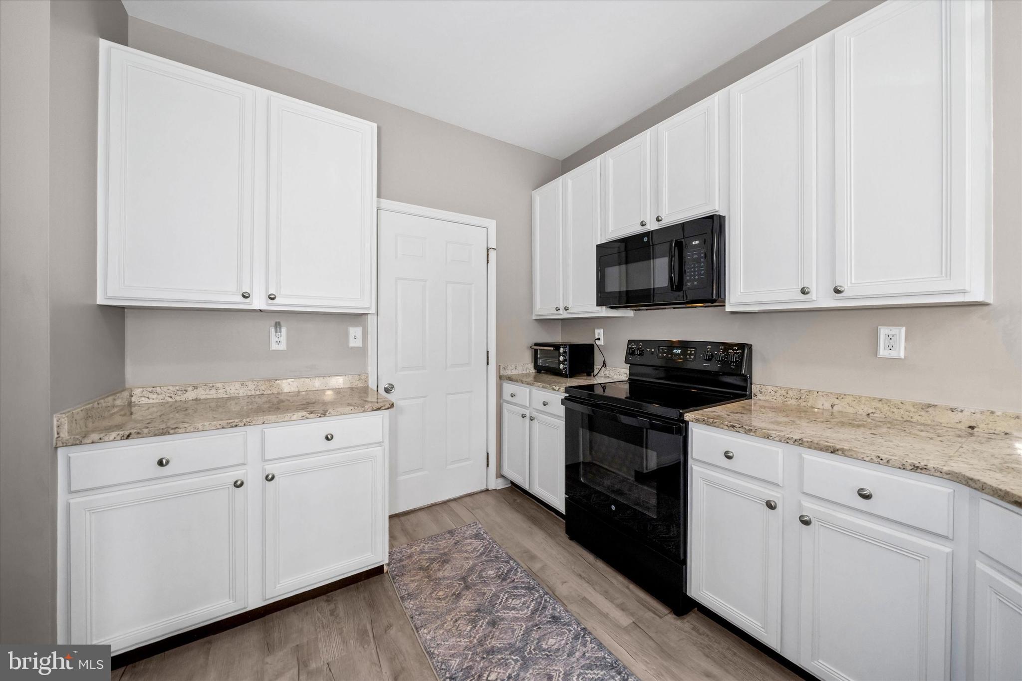 20 Hunters Way Glen Mills, PA 19342 - Photo 15 of 36 a kitchen with white cabinets and black appliances