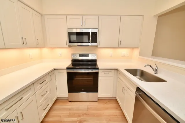 a kitchen with white cabinets sink and stainless steel appliances