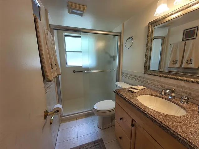 a bathroom with a granite countertop sink toilet and shower a mirror