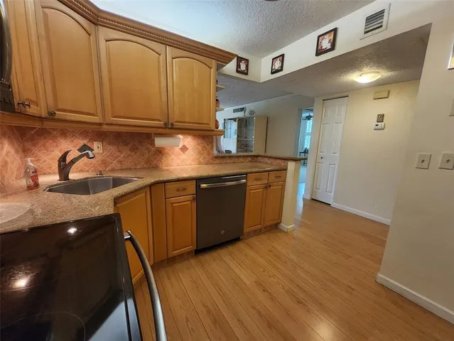 a kitchen with stainless steel appliances granite countertop a sink and cabinets with wooden floors