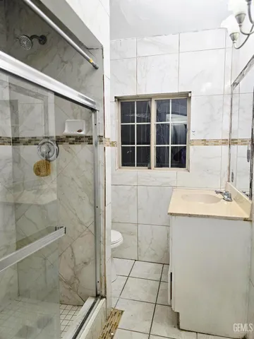 a bathroom with a granite countertop sink a toilet and shower
