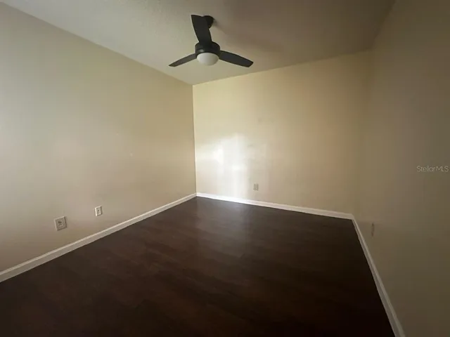 a view of room with hardwood floor and a ceiling fan