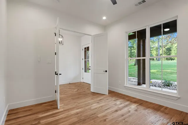 a view of a hallway with wooden floor and a bathroom