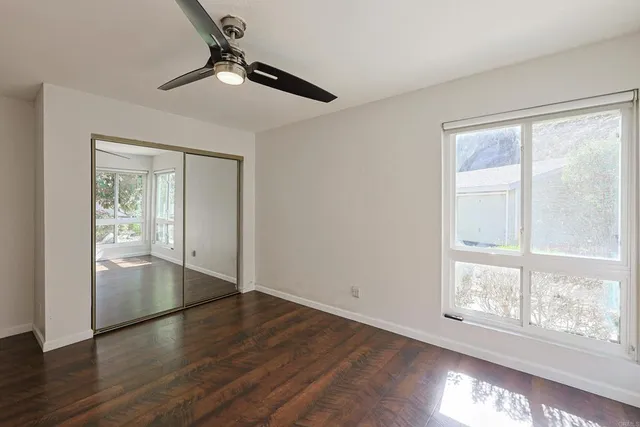 a view of empty room with wooden floor and fan