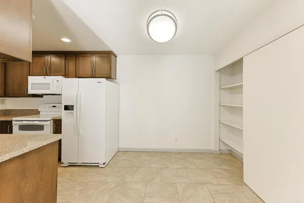 a kitchen with a refrigerator a stove top oven and white cabinets