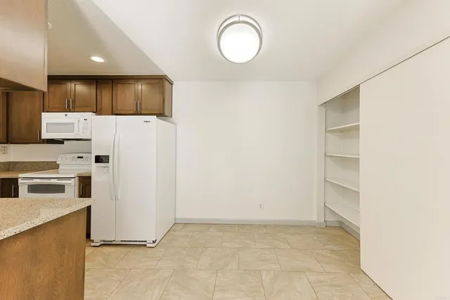 a kitchen with a refrigerator a stove top oven and white cabinets