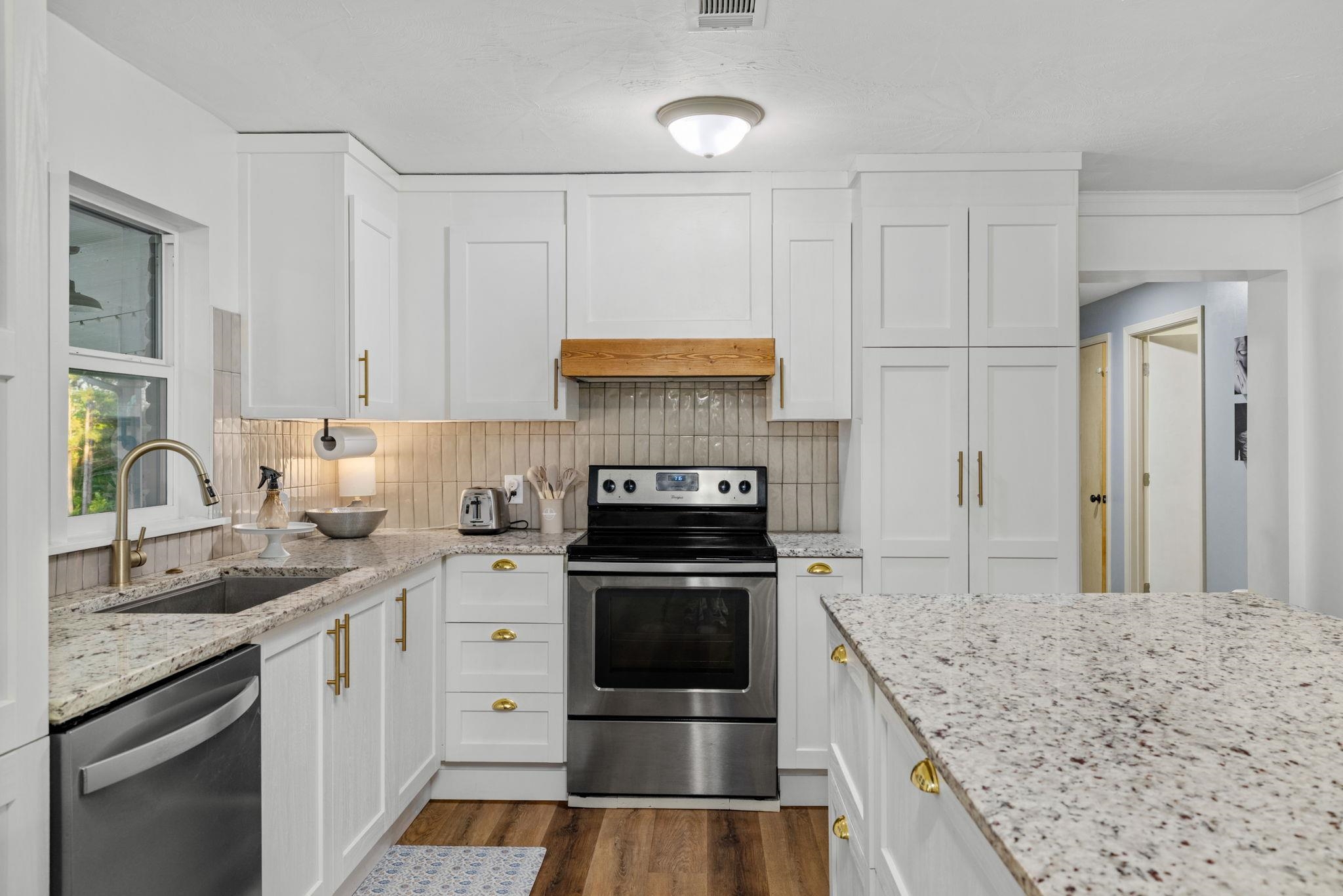 66 County Road 511 Corinth, MS 38834 - Photo 10 of 40 Kitchen featuring white shaker cabinetry, stainless steel appliances, light granite countertops, a tile backsplash, and wood-finish flooring