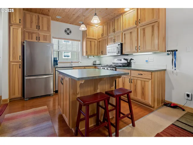 a kitchen with stainless steel appliances granite countertop a refrigerator a sink and white cabinets