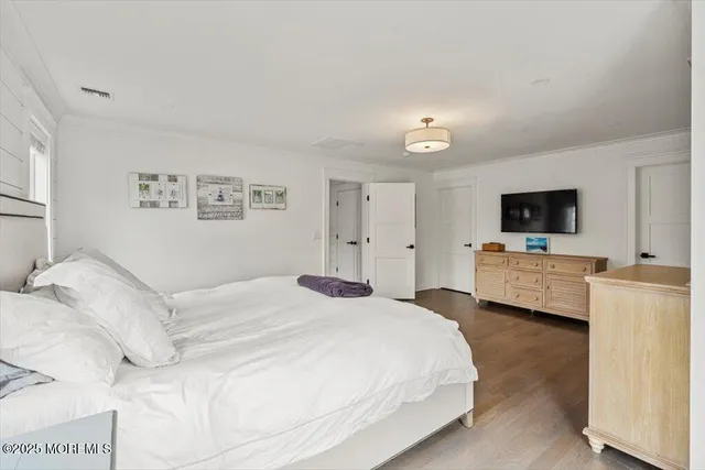 a spacious bedroom with a bed and a flat screen tv