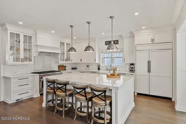 a kitchen with stainless steel appliances granite countertop a table chairs stove and white cabinets