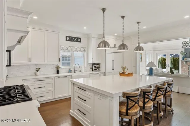 a kitchen with kitchen island granite countertop a sink a stove a dining table and chairs