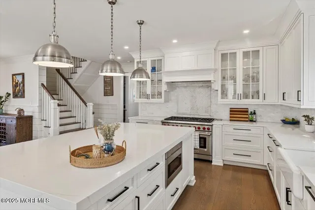 a kitchen with stainless steel appliances a stove a sink a chandelier and a dining table