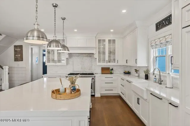 a kitchen with stainless steel appliances kitchen island granite countertop a sink a stove a refrigerator and cabinets