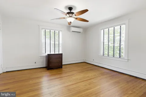 an empty room with wooden floor chandelier fan and windows