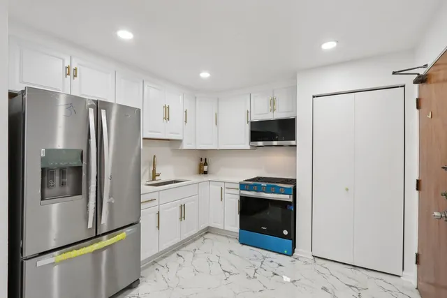 a kitchen with stainless steel appliances granite countertop a refrigerator a stove and a sink
