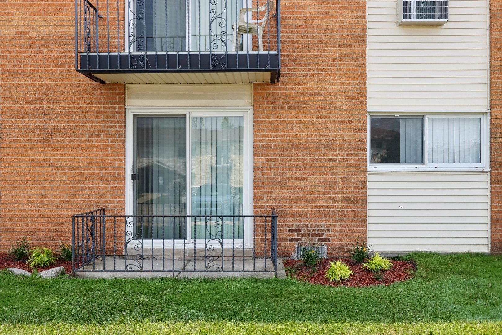 8916 Kenneth Drive, Unit 1E Des Plaines, IL 60016 - Photo 20 of 27 a view of a house with brick walls and a yard with plants