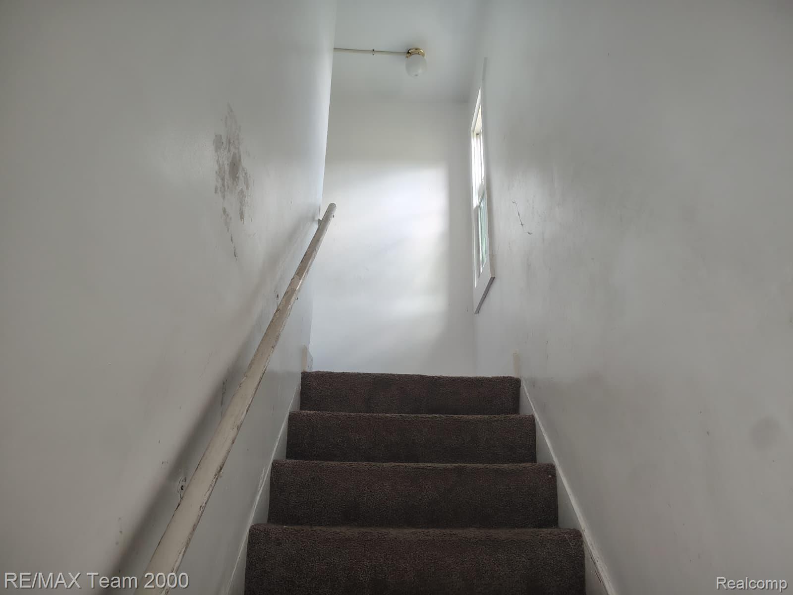 8860 Appoline Street Detroit, MI 48228 - Photo 38 of 45 Carpeted staircase with a window and a ceiling-mounted light fixture