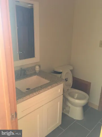 a bathroom with a granite countertop sink and a toilet