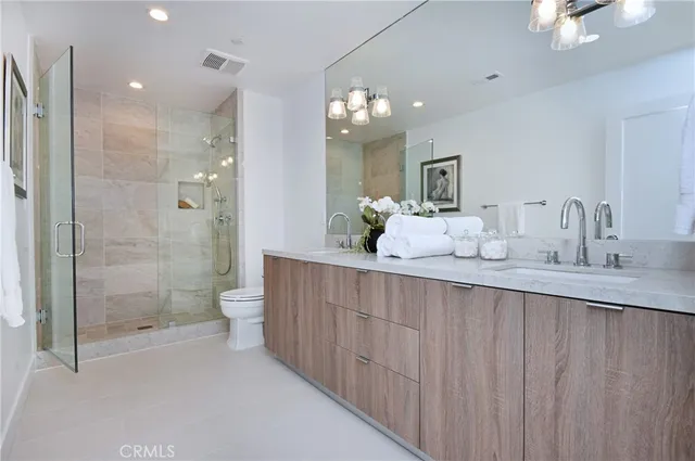 a bathroom with a double vanity sink mirror double shower and a toilet