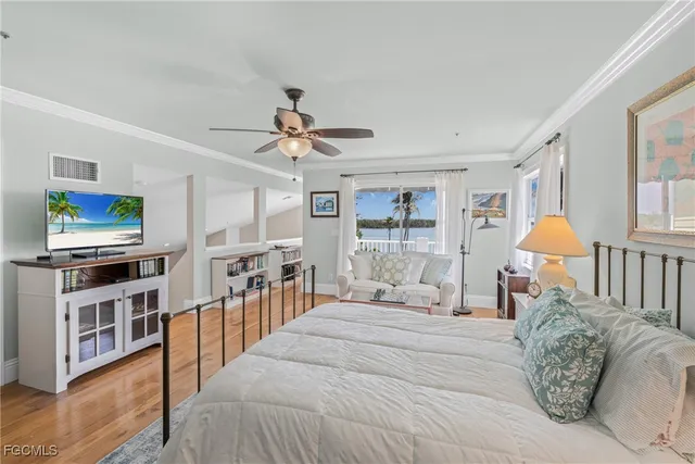 a bedroom with a bed a flat screen tv and a large window