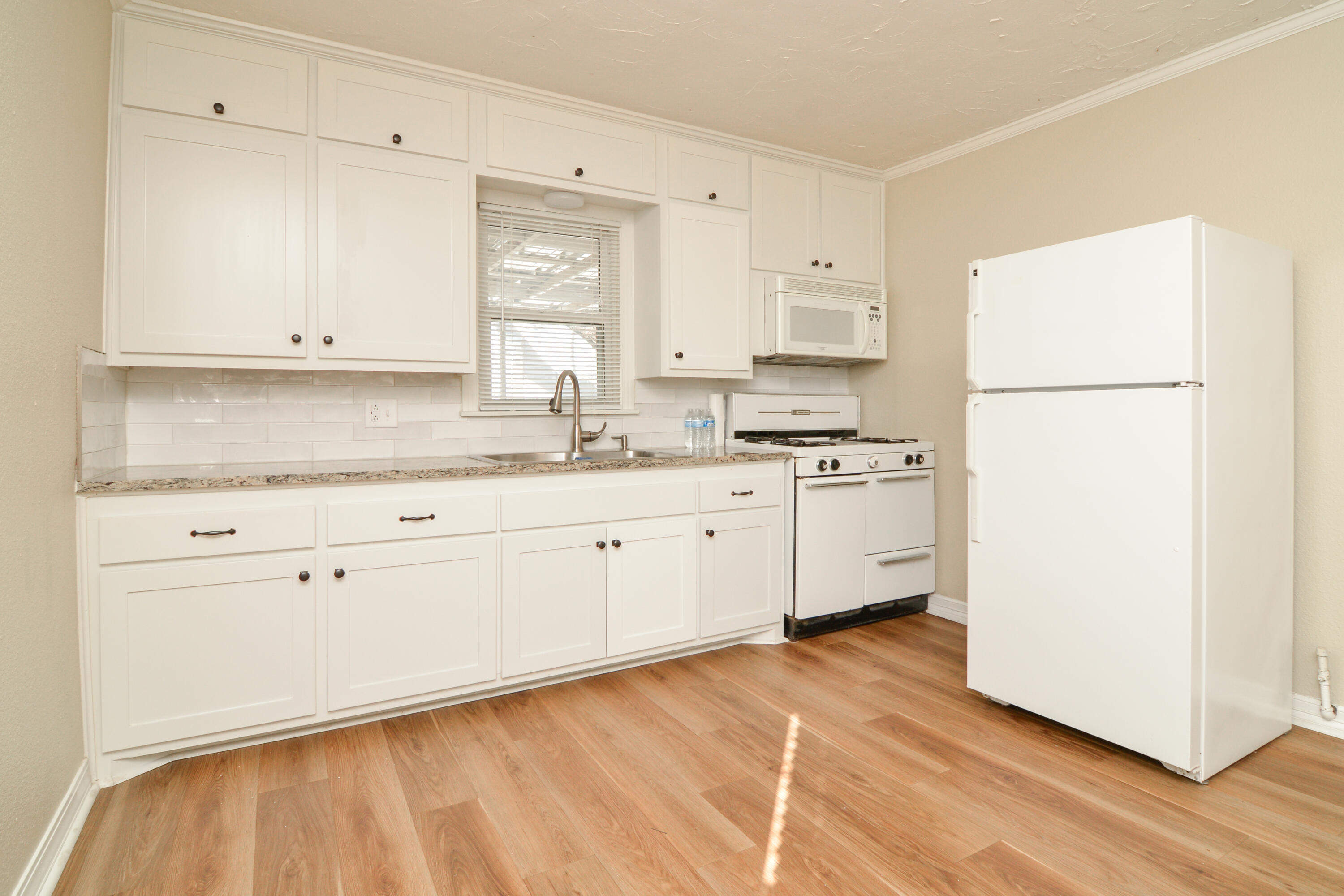 4907 41st Street Lubbock, TX 79414 - Photo 10 of 39 a kitchen with a sink a stove a refrigerator and white cabinets