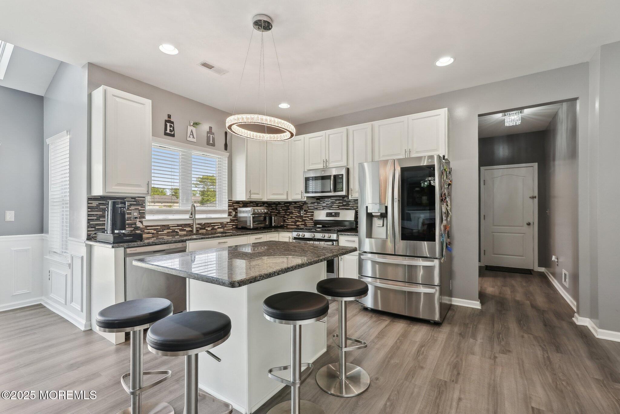 4 Bridle Path Bayville, NJ 08721 - Photo 17 of 44 a kitchen with stainless steel appliances kitchen island granite countertop a stove a refrigerator and white cabinets with wooden floor