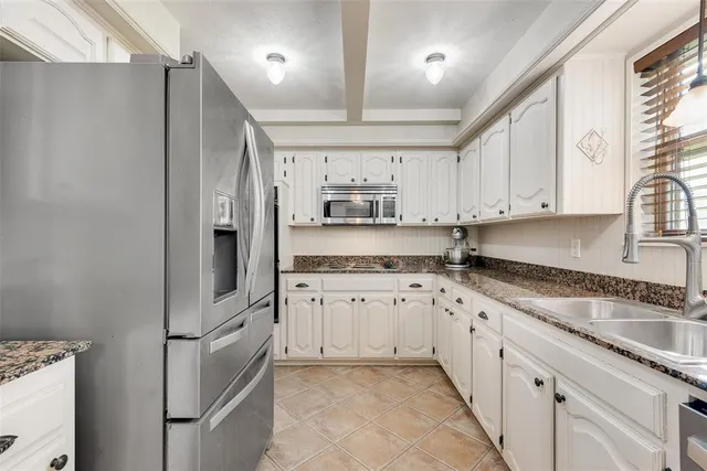 a kitchen with granite countertop a sink stove and refrigerator