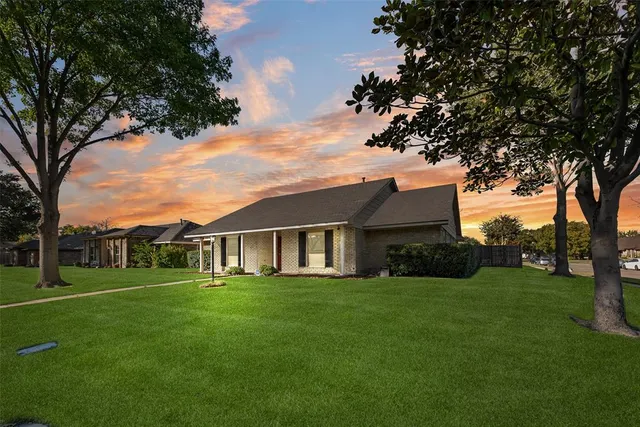 a view of a house next to a big yard and large trees