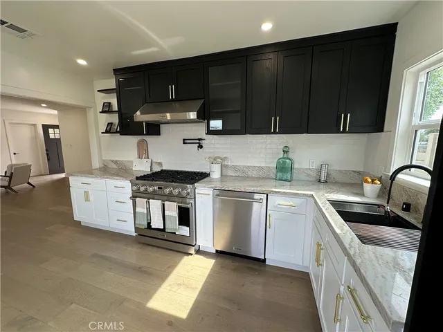 a kitchen with kitchen island granite countertop a sink a stove and cabinets