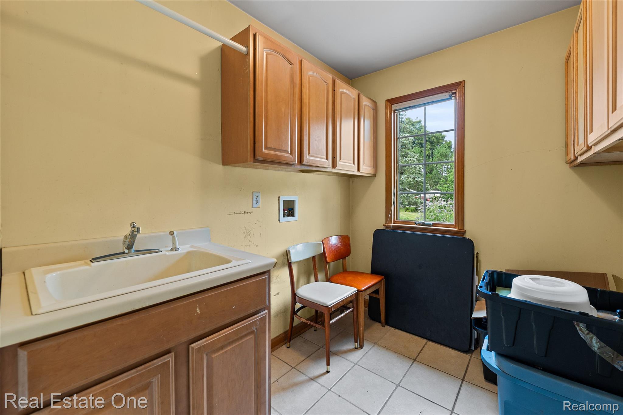 17268 Beech Daly Road Romulus, MI 48174 - Photo 45 of 60 Utility room with wood-finish cabinetry, a single basin sink, a window with wood trim, and a tile floor