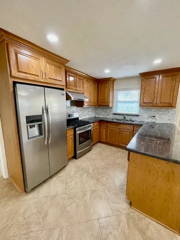 a kitchen with stainless steel appliances granite countertop a sink stove and refrigerator