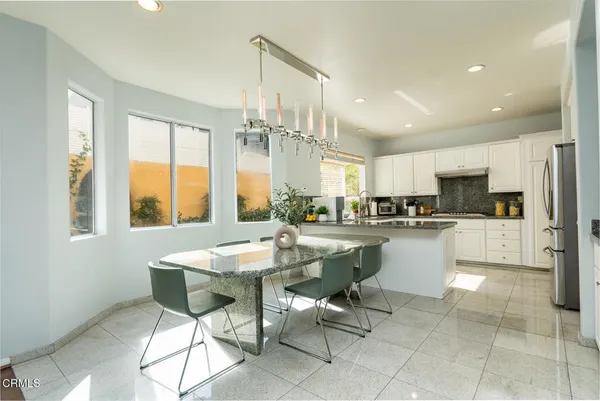 a kitchen with stainless steel appliances kitchen island granite countertop a table and chairs in it