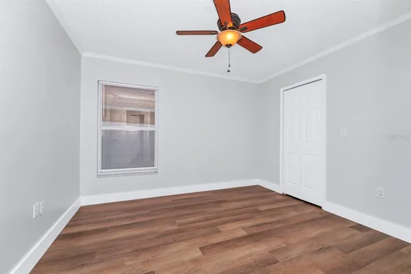 an empty room with wooden floor fan and windows